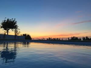 een zwembad met een zonsondergang op de achtergrond bij Antiga Fábrica de Chá in Nordestinho