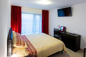 - une chambre avec un lit, un bureau et des rideaux rouges dans l'établissement Pensiunea Mateo, à Buzău