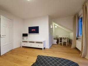 a living room with a tv on a white wall at Landhaus Haser in Oberammergau