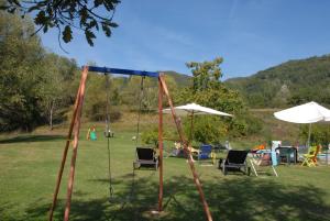 um baloiço num parque com cadeiras e guarda-sóis em La Capannella em Gallicano