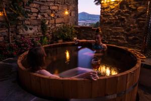 a boy and a girl in a hot tub with a glass of wine at O Chardinet d'a Formiga in Aínsa