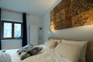 - un lit avec des draps et des oreillers blancs à côté d'une fenêtre dans l'établissement Al Maset di TSS' - Green Apartament - Zona Living Spaziosa - Perfetto per Famiglie Numerose a Pergine Valsugana, à Pergine Valsugana