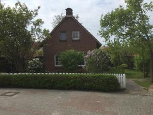 a red brick house with a white fence in front at Ferienhaus Schonerweg 9 in Norddeich in Norddeich