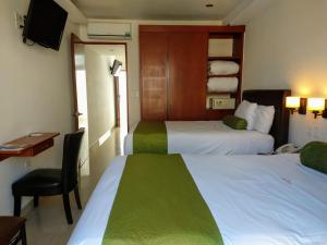 a hotel room with two beds and a chair at Suites La Concordia in Puebla