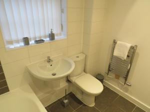 a white bathroom with a toilet and a sink at Hamilton Apartment in Doncaster