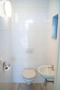 a white bathroom with a toilet and a sink at Beach Lodge in Callantsoog +29 photos