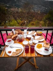 a wooden table with plates of food on it at Enchanted Hills Farmstay in Mukteswar