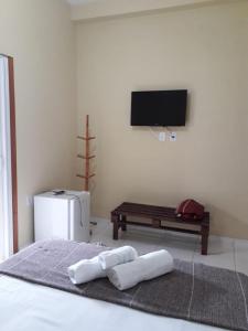 a bedroom with a tv and a bed with towels at Pousada O Tabuleiro in Jacumã