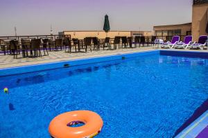 ein Schwimmbecken mit einem orangefarbenen Floß im Wasser in der Unterkunft Mirita Hotel ,10th Of Ramadan in Madinat Al Ashir min Ramadan