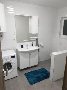 a white bathroom with a sink and a washing machine at Apartman LuMa in Baška Voda +18 photos