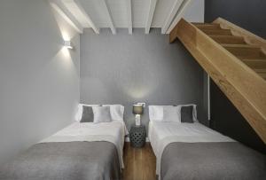 2 Betten in einem kleinen Zimmer mit einer Treppe in der Unterkunft Duplex Lux Escudo del Carmen in Granada