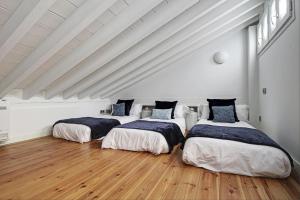 3 Betten in einem weißen Zimmer mit Holzböden in der Unterkunft Duplex Lux Escudo del Carmen in Granada