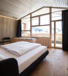sypialnia z dużym łóżkiem i dużym oknem w obiekcie HOLZGAUER HAUS w mieście Warth am Arlberg