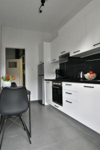 a kitchen with white cabinets and a chair in it at NY Central 3 in Patra