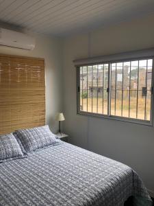 Un dormitorio con una cama y una ventana grande. en La Bruna, en Balneario Buenos Aires