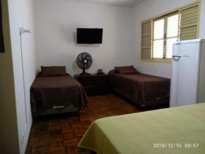 um quarto com 2 camas, um frigorífico e uma janela em CASA 230 - Guest House em Piracicaba