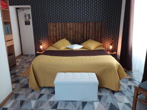 a bedroom with a bed with a yellow blanket and yellow pillows at Hôtel du Béarn in Bagnères-de-Bigorre