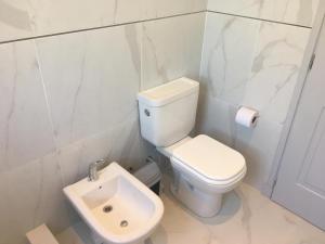 a white bathroom with a toilet and a sink at Titanes Pinamar in Pinamar