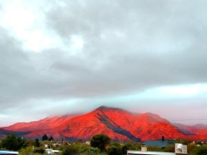 a view of a red mountain under a cloudy sky at El Mundo Interior in Capilla del Monte