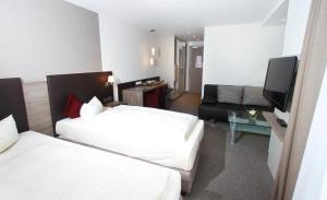 Habitación de hotel con 2 camas y sofá en Landhotel Geiselwind en Geiselwind