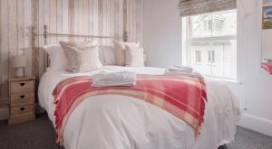 1 dormitorio con 1 cama con manta roja y blanca en Corner Cottage Mevagissey en Mevagissey