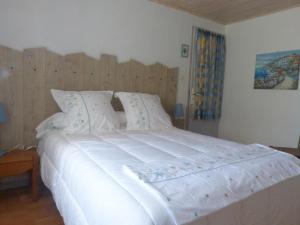 a bedroom with a large white bed with a wooden headboard at LA MAISON BLEUE in Saint-Gelais