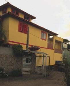 Casa amarilla con ventanas rojas y puerta en Pousada TonaPraia, en Florianópolis