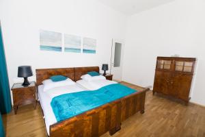 Schlafzimmer mit einem großen Holzbett mit blauer Bettwäsche in der Unterkunft Rosenstein Apartments by Family & Home in Wien