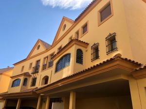 ein gelbes Gebäude mit Fenstern und Balkonen darauf in der Unterkunft Luxurious duplex penthouse with golf and sea views in Benalmádena