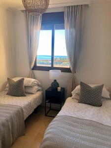 Un dormitorio con dos camas y una ventana. en Luxurious duplex penthouse with golf and sea views, en Benalmádena