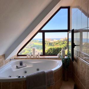 un bagno con vasca e ampia finestra di Luxurious duplex penthouse with golf and sea views a Benalmádena
