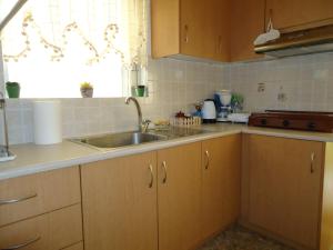 a kitchen with wooden cabinets and a sink at Ενοικιαζόμενα δωμάτια "ΟΛΓΑ" in Loutra Ipatis