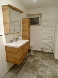 a bathroom with a white sink and wooden cabinets at Landhaus Rathgeb in Bad Gastein