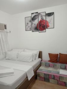 a bedroom with a bed with four pictures on the wall at 2BR townhouses good for 12pax each & NETFLIX & 100Mbps WIFI & pool resort 2min walk & 3km outside Pico de Loro Cove & Calayo Cove - with Endorsement for Pico de Loro Cove daytour & Boat-Tour & Island Hopping assistance in Nasugbu