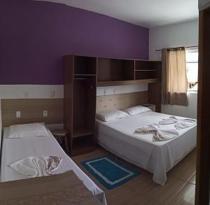 2 camas en una habitación con paredes moradas en Pousada Mares de Penha, en Penha