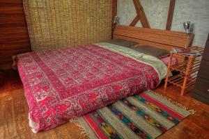 a bedroom with a bed with a red comforter and a table at 435 in Ishigaki Island