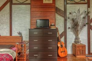 a bedroom with a dresser with a television and a guitar at 435 in Ishigaki Island