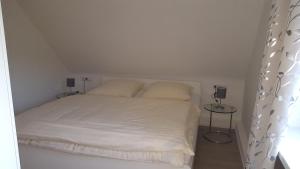 1 dormitorio con 1 cama blanca y 2 almohadas en Ferienwohnung Haus Zeier, en Hahnenklee-Bockswiese