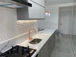 a white kitchen with a sink and a stove at Flat na Barra - Vista para o Mar in Rio de Janeiro