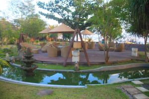 a pond in a yard with a table and chairs at Hotel Uyah Amed Spa Resort in Amed