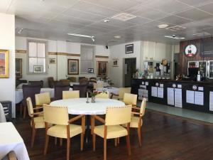 une salle à manger avec une table et des chaises blanches dans l'établissement Club Boutique Hotel Cunnamulla, à Cunnamulla