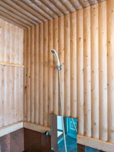 a shower in a room with a wooden wall at Pension Starlight Azumi in Hakuba