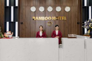 Due donne in piedi dietro un bancone di fronte a un edificio di Bamboo Hotel a Da Nang