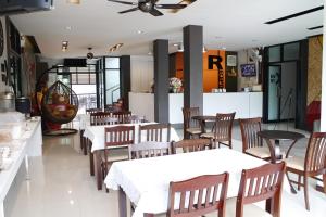 a restaurant with white tables and wooden chairs at The Siri Place in Udon Thani