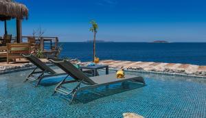 a pool with two chairs and a table and the ocean at Mandalina Suites in Kaş