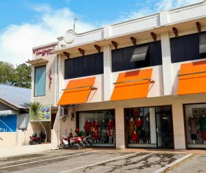 a building with orange windows and motorcycles parked outside at OYO 1686 Lenggogeni House in Padang