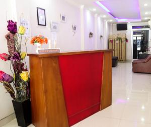 a red counter in a lobby with flowers at OYO 1686 Lenggogeni House in Padang