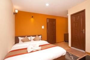 sypialnia z dużym łóżkiem z pomarańczową ścianą w obiekcie Holiday Hostel w Katmandu
