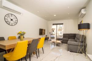 a dining room and living room with a table and yellow chairs at Eshel Suites Even Israel in Jerusalem