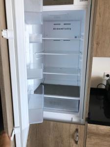 an empty white refrigerator with its door open at OCEAN SUNSET in Saint-Leu